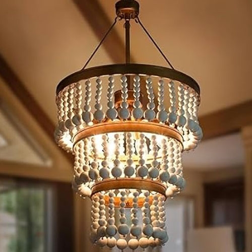 A beaded 3-tier chandelier featuring cascading strands of round, light-colored beads suspended from a dark metal frame, offering a layered, elegant design that diffuses soft light.