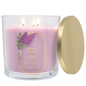 A lavender-colored scented candle labeled \“Lilac Fields\“ with notes of lilac, jasmine, and lily, in a clear jar with a gold lid, weighing 14 oz (397 g).