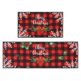 Two rectangular, red and black plaid mats featuring \“Merry Christmas\“ text, adorned with snowflakes and festive greenery accents.
