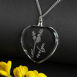 Heart-shaped crystal necklace pendant featuring an etched floral design and the name \“Evelyn,\“ accompanied by a silver chain.