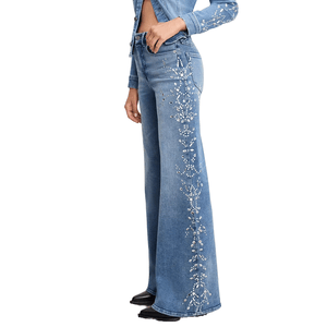 High-waisted blue denim flare jeans with floral bead and rhinestone embellishments running along the sides. Paired with a matching cropped denim jacket.