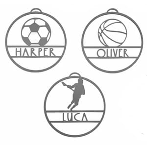 Three circular personalized sports-themed name tags with soccer, basketball, and baseball designs labeled \“HARPER,\“ \“OLIVER,\“ and \“LUCA.\“