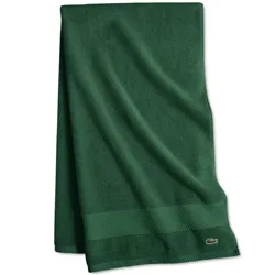 A dark green towel featuring a textured border and an embroidered crocodile logo in the corner.