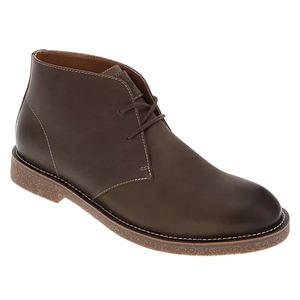 A brown leather chukka boot with a simple lace-up design and contrasting stitching, featuring a textured, light-brown sole.