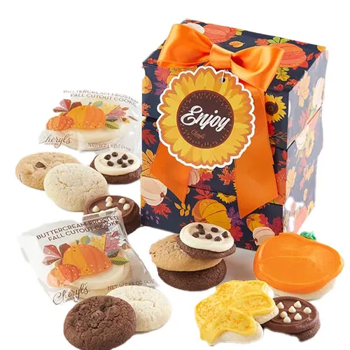 Gift box with an orange bow, featuring a variety of fall-themed cookies including chocolate chip, buttercream frosted, and pumpkin-shaped designs, with colorful autumn leaf patterns on the packaging.