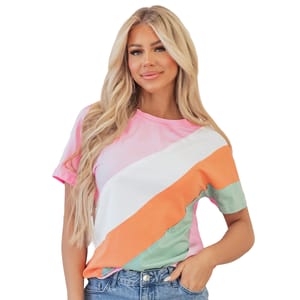A casual, short-sleeve colorblock top featuring diagonal stripes in pink, white, orange, and green, paired with blue jeans. The top has a round neckline and a relaxed fit.