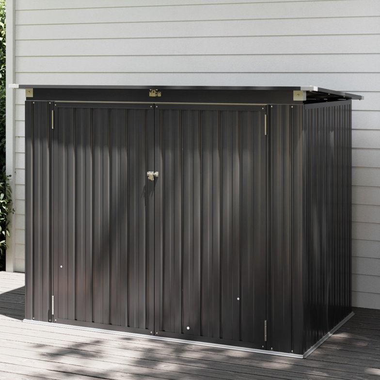 A compact, dark gray metal storage shed with a sloped roof and double doors secured by a lock, positioned on a wooden deck beside light-colored siding.