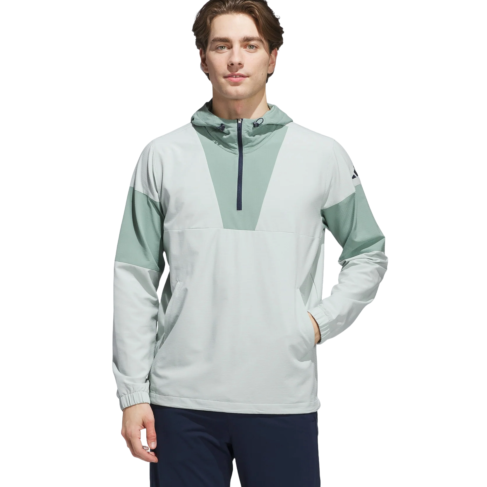 A man wears a light gray and mint green hooded pullover with a quarter-zip front and long sleeves, paired with dark pants.