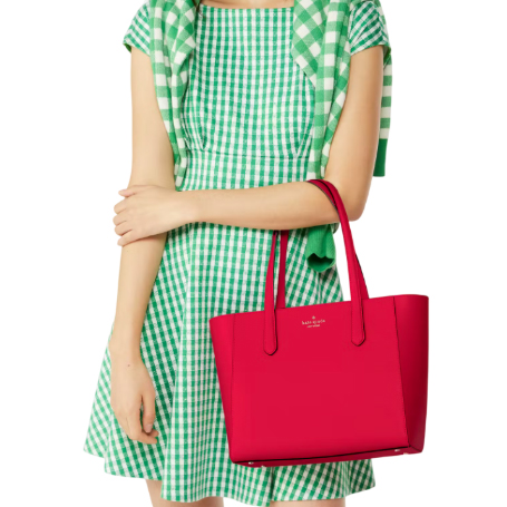 A bright pink Kate Spade leather tote with two handles, featuring a simple and sleek design with the brand logo on the front.