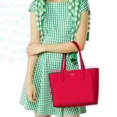 A bright pink Kate Spade leather tote with two handles, featuring a simple and sleek design with the brand logo on the front.
