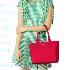 A bright pink Kate Spade leather tote with two handles, featuring a simple and sleek design with the brand logo on the front.