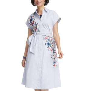 A light blue belted shirtdress with floral embroidery on the top right and lower left, featuring short sleeves and a collar.