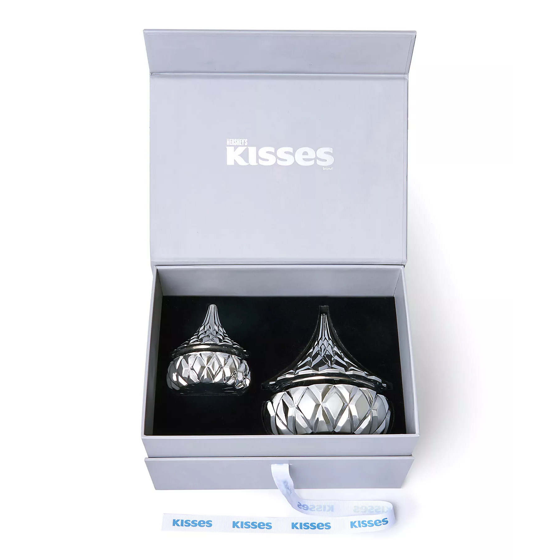 A gift box contains two crystal containers shaped like Hershey's Kisses, with intricate cut glass patterns and a blue \“Kisses\“ ribbon inside.