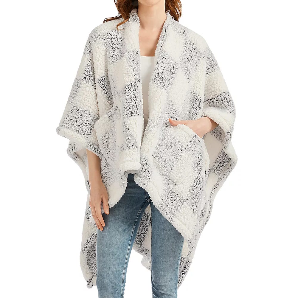 A cozy, plaid Sherpa wearable throw with an open front design, featuring large front pockets, and soft, textured material, worn over a white top and jeans.