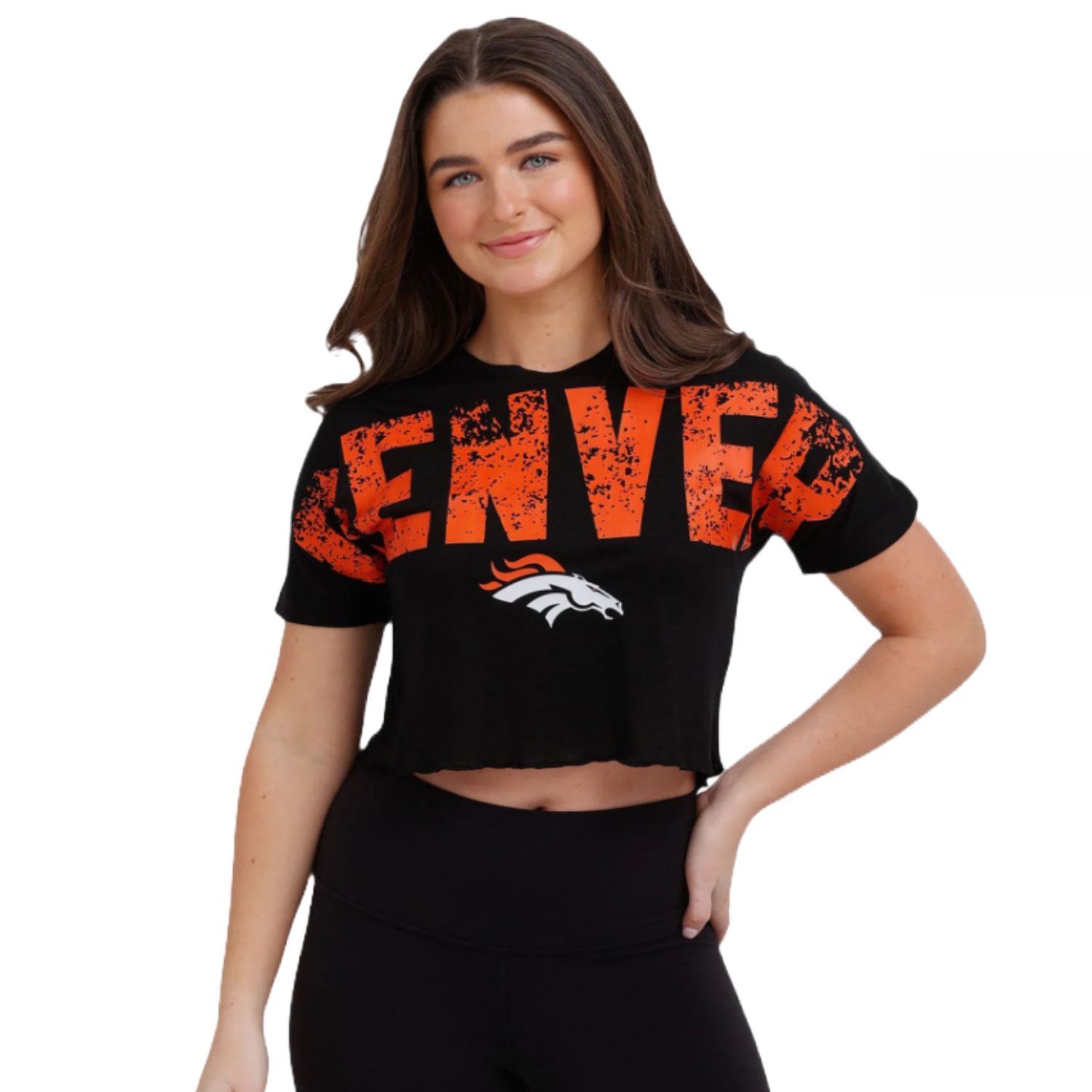 A woman is wearing a black crop top with \“Denver\“ in large distressed orange letters and a Denver Broncos logo. She is also wearing black leggings.