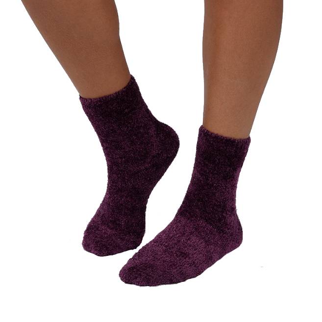 A pair of soft, fluffy, dark purple socks worn on feet.