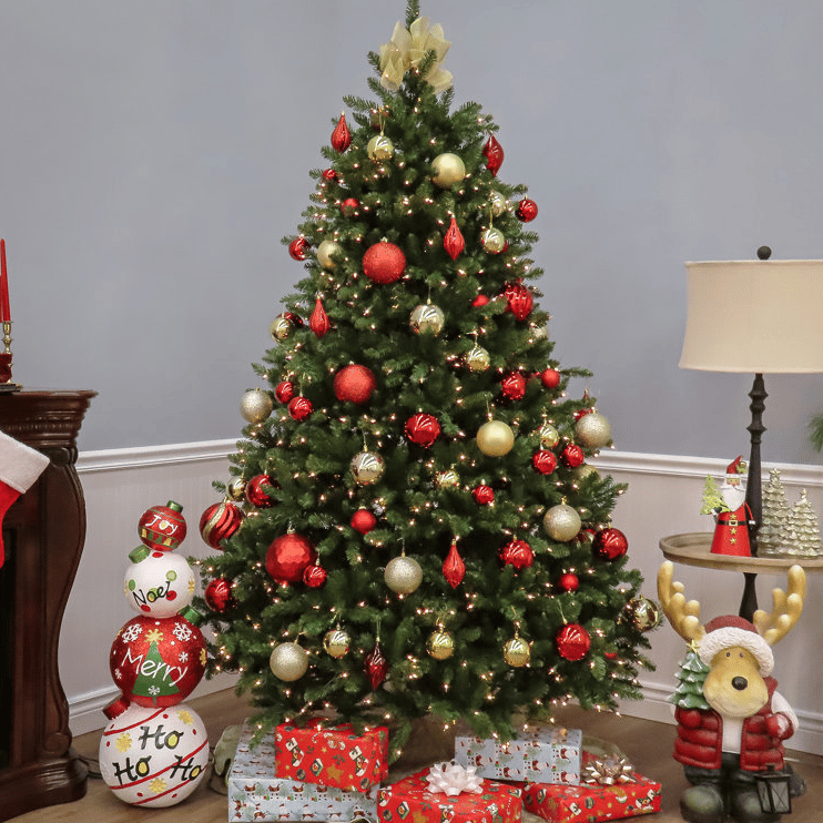 7.5' Fir Christmas Tree with clear lights, adorned with red and gold ornaments. Presents wrapped in festive paper sit beneath, alongside a holiday-themed sculpture and decorative candles on a nearby table.