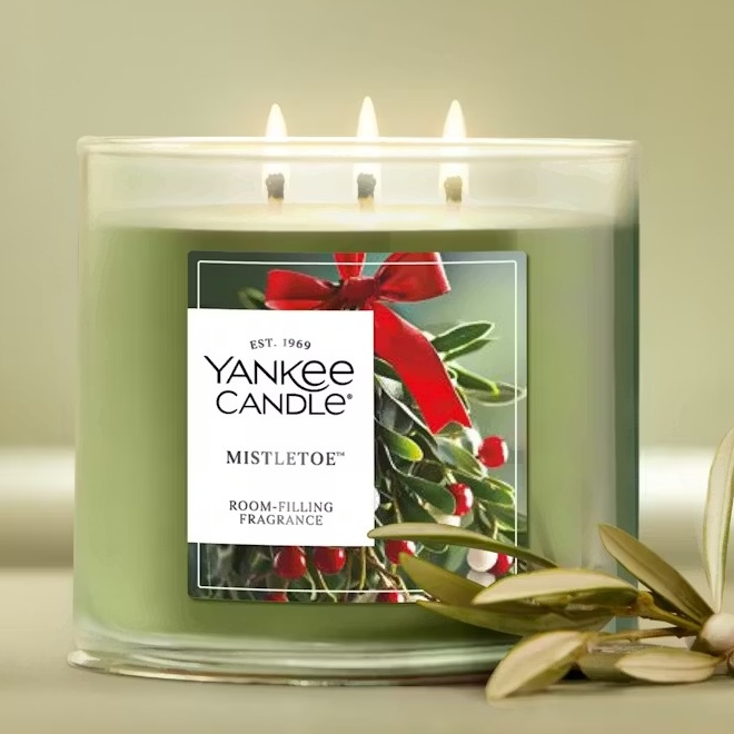 Yankee Candle Mistletoe scented candle with three wicks and green wax, featuring a label with mistletoe imagery and the text \“room-filling fragrance.\“