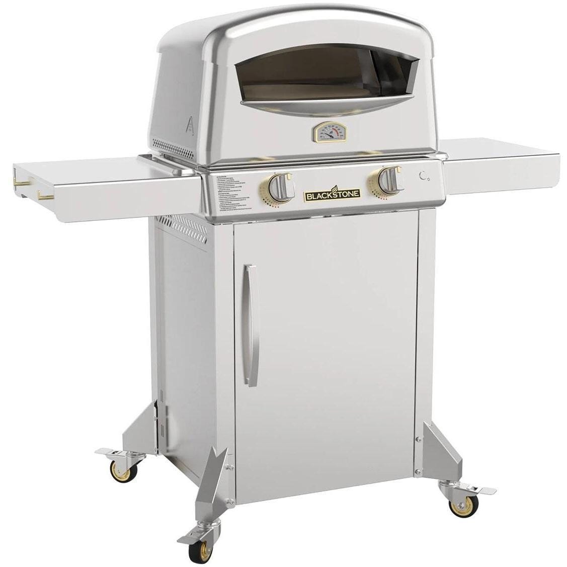 The Blackstone Pizza Oven is a stainless steel outdoor pizza oven with a thermometer and controls on the front panel. It features collapsible side shelves and has wheels for mobility.