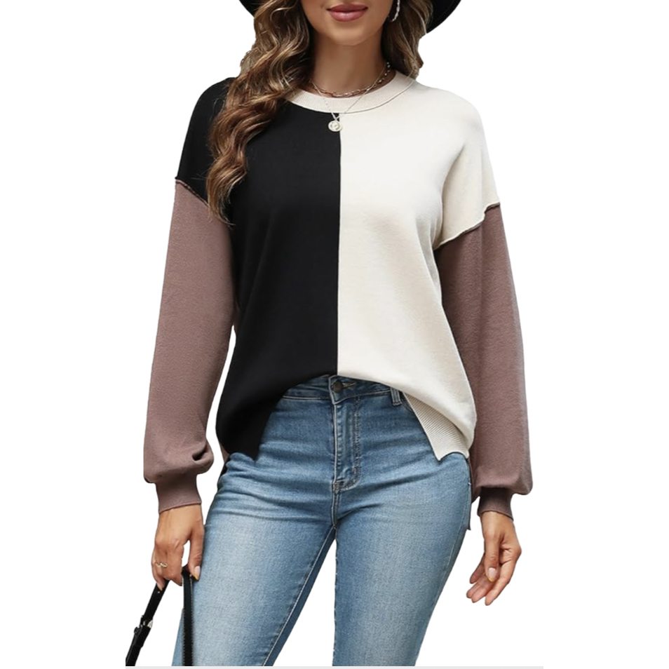 A stylish women's colorblock sweater featuring a black and white split design on the front, with light brown sleeves. It's paired with blue jeans and accessorized with a necklace and hat for a casual look.