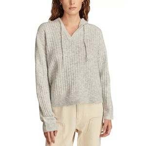 Light gray, ribbed hooded sweater with a V-neck and drawstrings, paired with cream-colored pants.