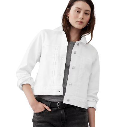 A person wearing a white denim jacket over a gray shirt, paired with dark jeans and a black belt.