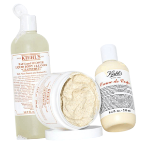 Three Kiehl's products: a 16.9 fl. oz. Bath and Shower Liquid Body Cleanser in \“Grapefruit,\“ a body scrub in a jar, and an 8.4 fl. oz. bottle of Creme de Corps body lotion.