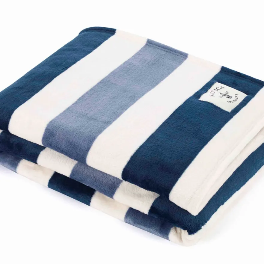 A folded blanket featuring wide, horizontal stripes in navy blue, light blue, and white with a small branded label.