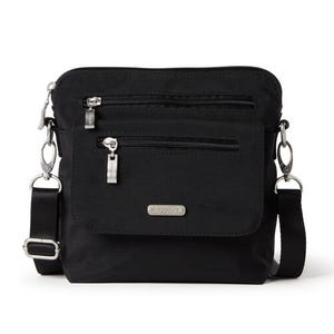 A black crossbody bag with two zippered front pockets, detachable strap, and metal brand plaque.