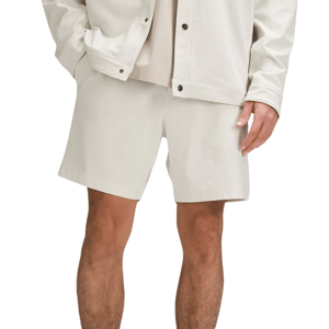 Male model wearing white shorts, white jacket, and white socks paired with dark slippers.