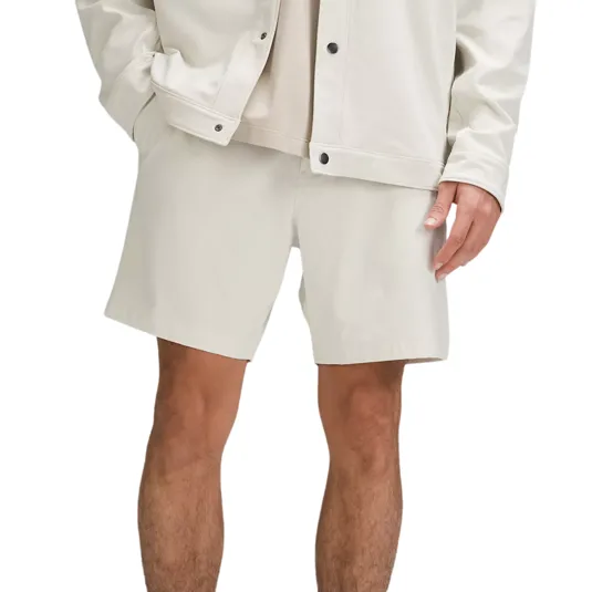 Male model wearing white shorts, white jacket, and white socks paired with dark slippers.