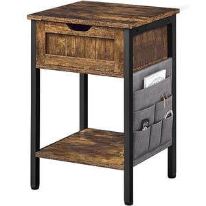 Wooden side table with a drawer, an open lower shelf, and a fabric side pocket for additional storage, supported by black metal legs.