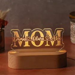 A decorative LED light with the word \“MOM\“ features personalized names \“Emma,\“ \“Olivia,\“ and \“Alex\“ written stylishly across it. It is mounted on a wooden base.