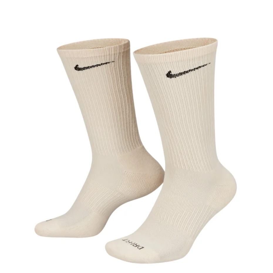 A set of six pairs of Nike socks in various shades of beige, pink, and brown, featuring a black swoosh logo and \“DRI-FIT\“ text.