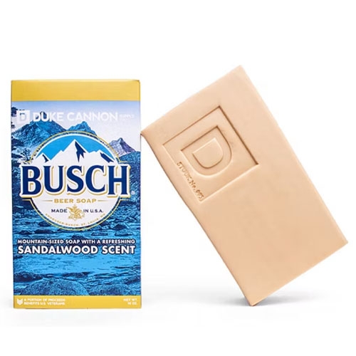 Duke Cannon Busch Beer Soap features a refreshing sandalwood scent and comes in a mountain-sized bar. Made in the USA, the soap package displays a mountain scene and the Busch brand logo, measuring a substantial 10 oz.