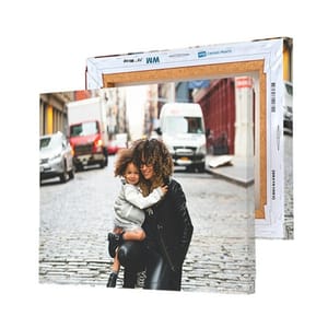 Two canvas prints of a mother and child embraced on a cobblestone street, with one facing forward and the other showing the back frame, displaying the construction details.