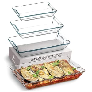 A 4-piece glass bakeware set featuring four rectangular dishes of varying sizes, ideal for baking and serving. One dish is shown with a baked eggplant and tomato dish.
