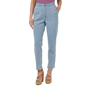 Light blue jeans with an elastic waistband, front pockets, and a button closure are worn by a person paired with tan wedge sandals and a purple top.