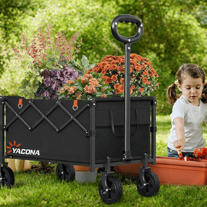 A collapsible garden wagon labeled \“YACONA\“ filled with flowers is next to a child gardening with a spade in a planter outdoors.