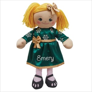 A plush doll with yellow yarn hair, wearing a green dress adorned with snowflakes and a gold bow, personalized with the name \“Emery.\“ The doll has striped pink socks and black shoes.