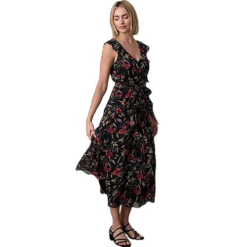 A woman is wearing a sleeveless, black floral maxi dress with red and green patterns, paired with black sandals.
