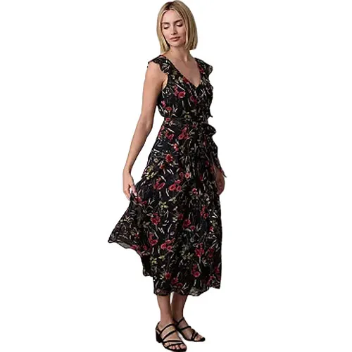 A woman is wearing a sleeveless, black floral maxi dress with red and green patterns, paired with black sandals.