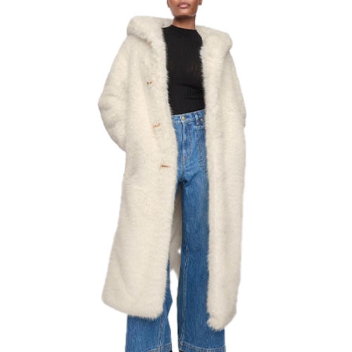 A woman wearing a long white faux fur coat, black top, and blue jeans.