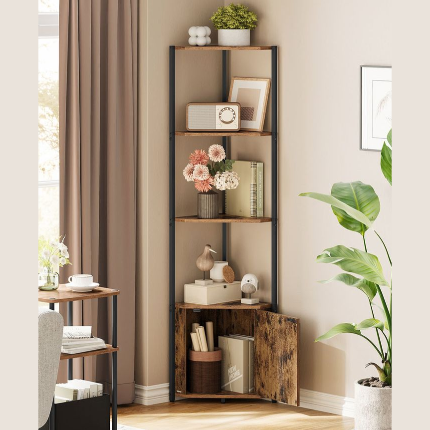 A corner bookshelf with four wooden shelves and black metal supports displays decorative items including flowers, framed art, books, and small sculptures. A potted plant stands nearby, enhancing the cozy corner setup.