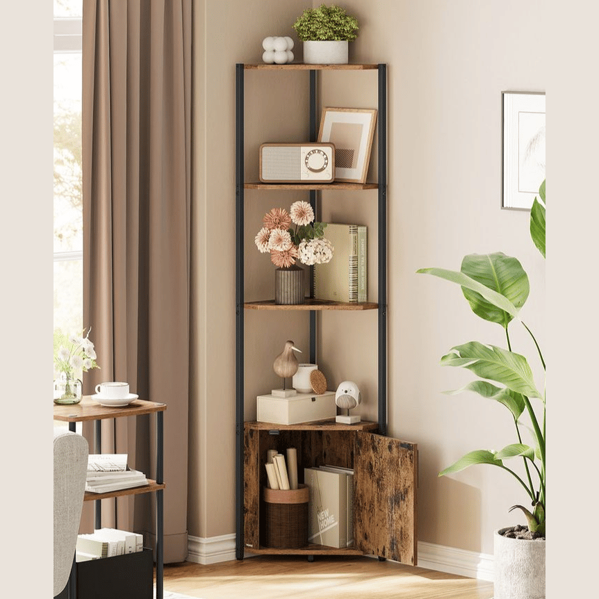 A corner bookshelf with four wooden shelves and black metal supports displays decorative items including flowers, framed art, books, and small sculptures. A potted plant stands nearby, enhancing the cozy corner setup.