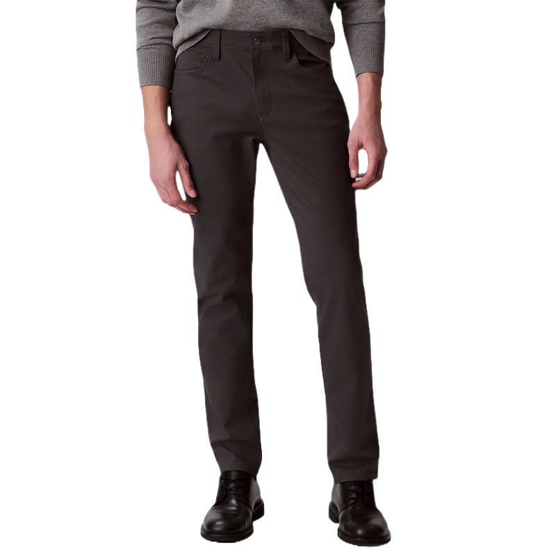 Calvin Klein Slim-Fit Pants are dark-colored, tailored trousers designed for a sleek and modern silhouette. They feature a button and zipper closure, belt loops, and are paired with black shoes and a gray sweater for a stylish, sophisticated look.