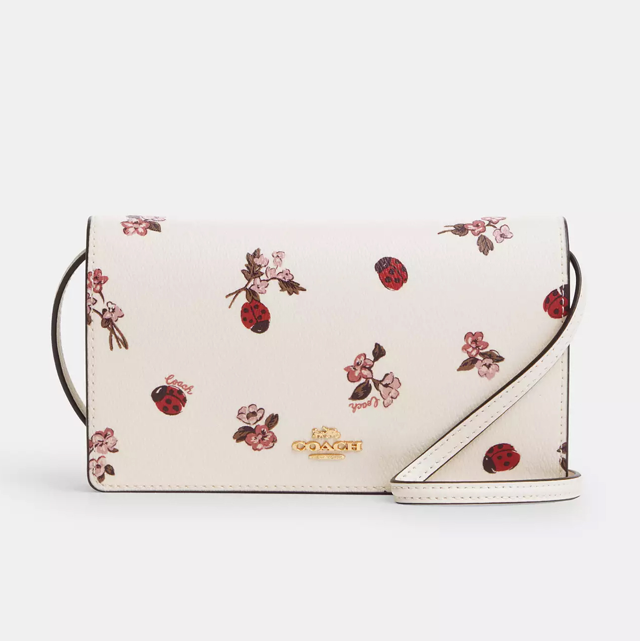 White crossbody clutch with a floral and ladybug pattern, featuring a fold-over flap and a detachable shoulder strap.