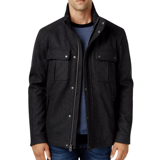 A man is wearing a dark grey jacket with snap-button pockets over a blue textured sweater, paired with blue jeans.