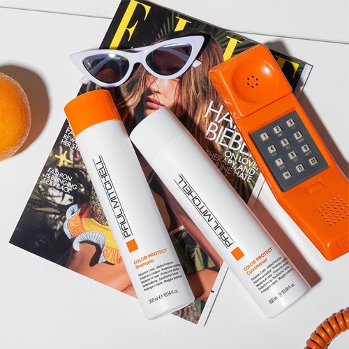 a white shampoo and conditioner besides an orange and an orange phone