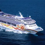 A cruise ship sailing on the ocean, with colorful sun-themed artwork on its side and the name \“Norwegian Sun\“ visible on the hull.